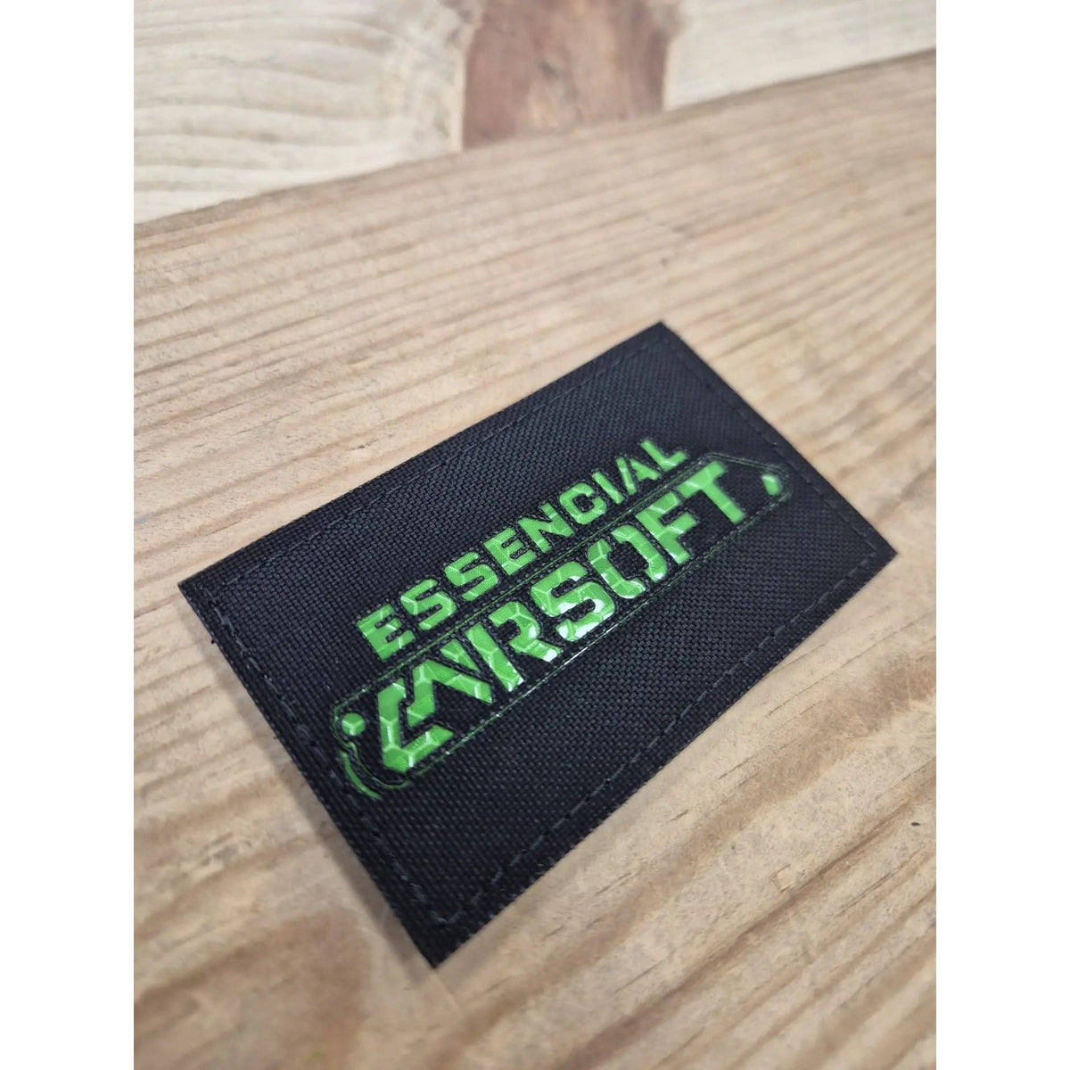 Patch Lasercut Essencial Airsoft Made in France de taille 8x5cm en Cordura noir sur fond vert, idéal pour plate carrier, combat shirt, casque